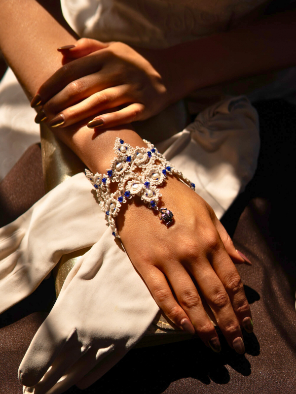 Close-up of the Time for Tea tatted lace bracelet on a model’s wrist, pearls and