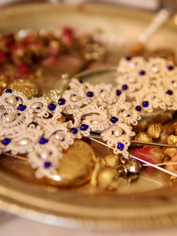 Handmade lace bracelet with pearls and blue beads displayed vintage-style