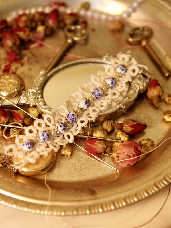 Tatted lace bracelet with blue porcelain beads on vintage silver tray