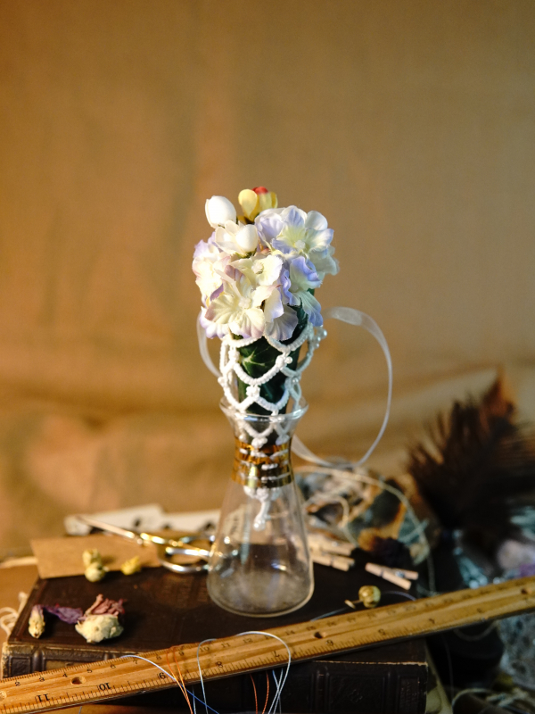 Everpetal Ornament White lace cone ornament with soft florals shown in a vintage book vignette