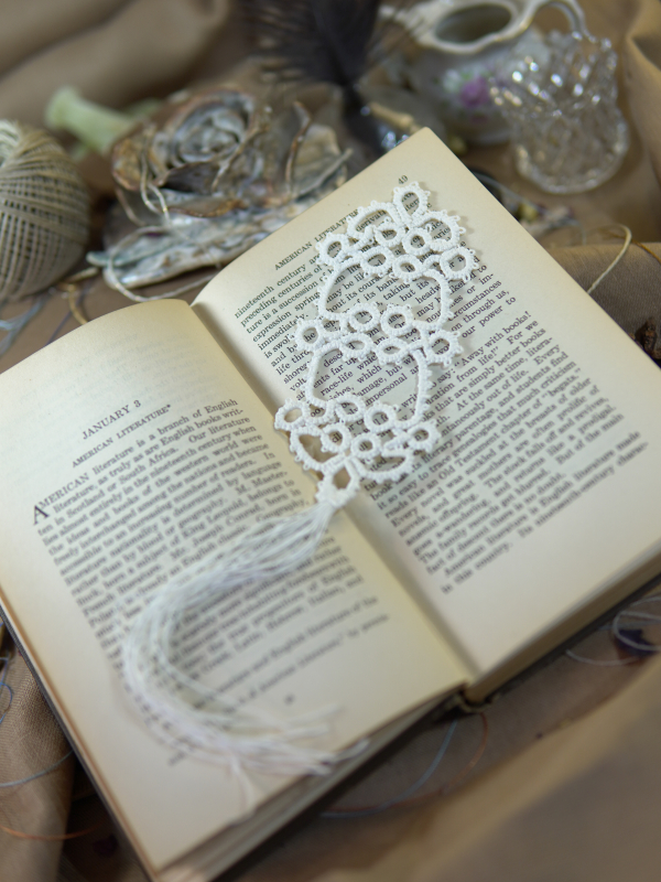 Snowlace Bookmark White tatted lace bookmark with tassel resting across pages of an open book