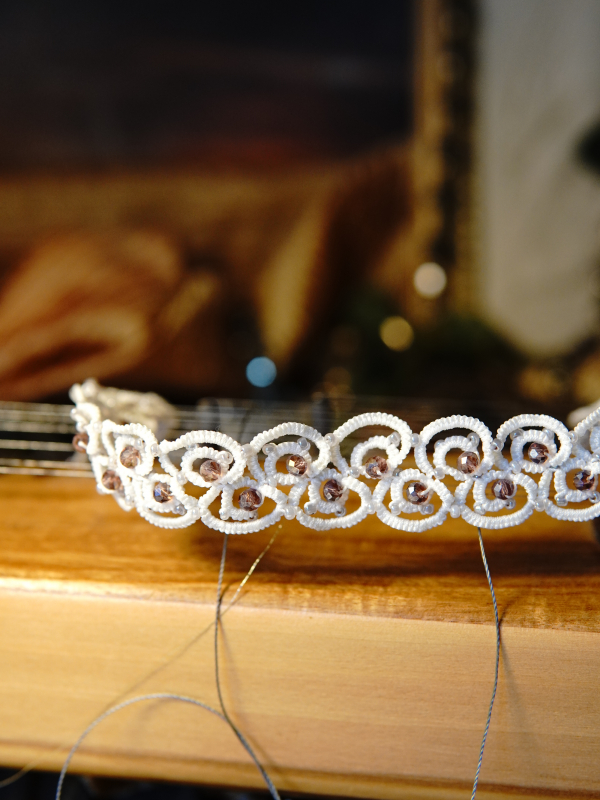Elarian Bloom Necklace with crystals White lace choker draped across a wooden instrument.