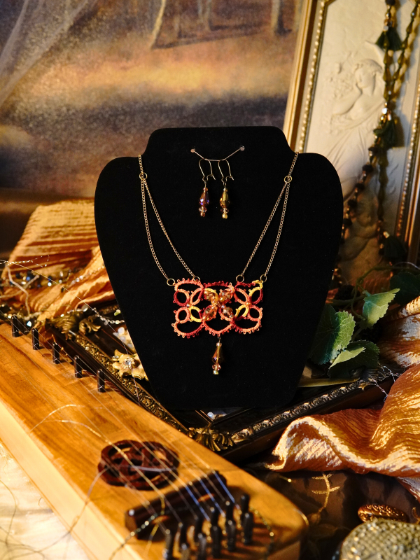 The Gilded Emberleaf tatted necklace in rust and gold Necklace set shown on black display with warm lighting