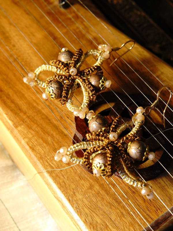 Hearthshade folded-ring tatted lace earrings in warm tones Brown and cream tatted earrings with gold beads on instrument