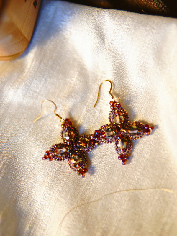 Starweft Blossom tatted lace earrings in pink and crystal Crystal-centered tatted earrings arranged on soft fabric.