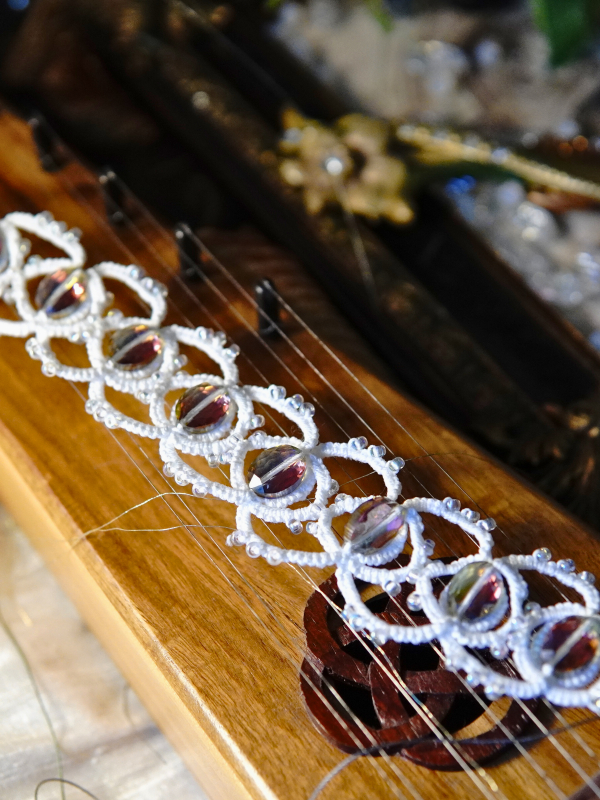 Whisperbind Bracelet – White Tatted Lace with Aurora Borealis Crystals Whisperbind bracelet on wooden instrument