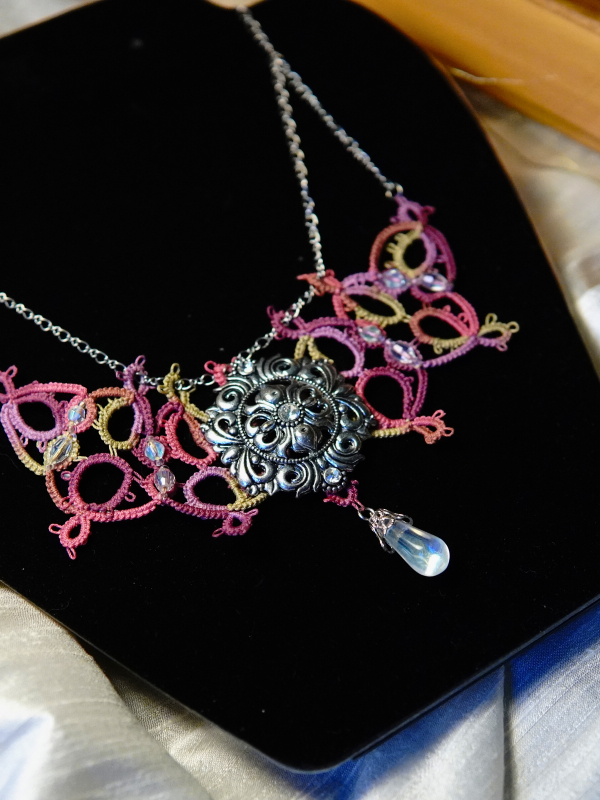 Raspberry Rain tatted necklace with silver sigil and crystal drop Elven-style tatted necklace in pink and green displayed on black bust