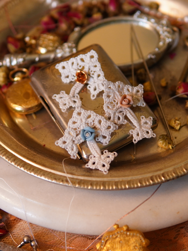 White lace cross keepsakes with rose centers on a vintage silver plate