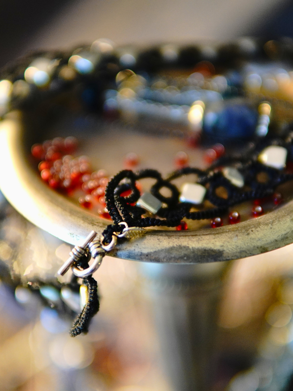 Ironveil Oath—midnight lace and silvered resolve Ironveil Oath necklace draped on metal candle stand