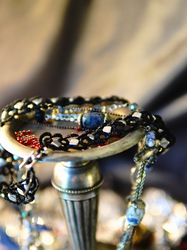 Ironveil Oath—midnight lace and silvered resolve Detailed view of silver-beaded black lace necklace against textured metal.