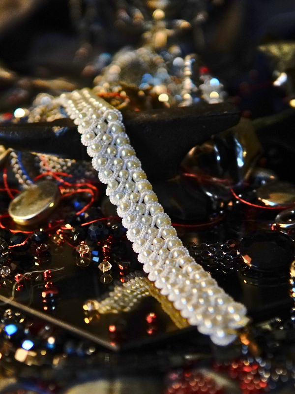 Vowguard bracelet in white lace and pearl Vowguard bracelet laid flat across Oathforged backdrop