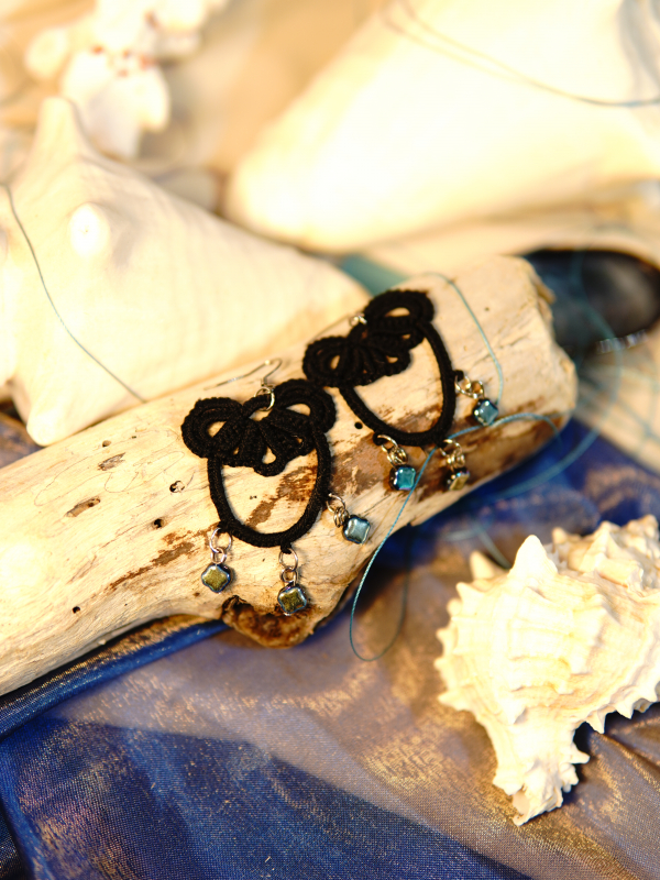 Midnight Tide tatted lace earrings in deep-sea black Earrings displayed with driftwood and seashell props