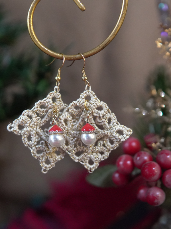 Christmas tatted diamond earrings photographed against a blurred holiday backdro