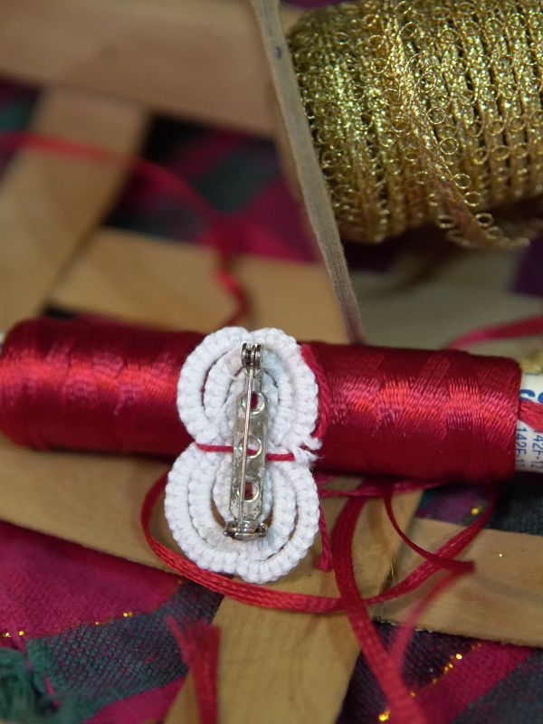 White tatted snowman pin with silver clasp on back