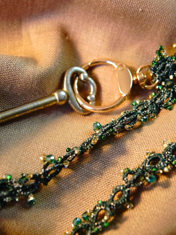 Green tatted lanyard with beads coiled on tan cloth
