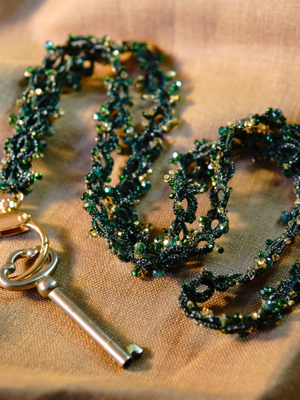 Dark green beaded tatted lanyard displayed neatly on cloth
