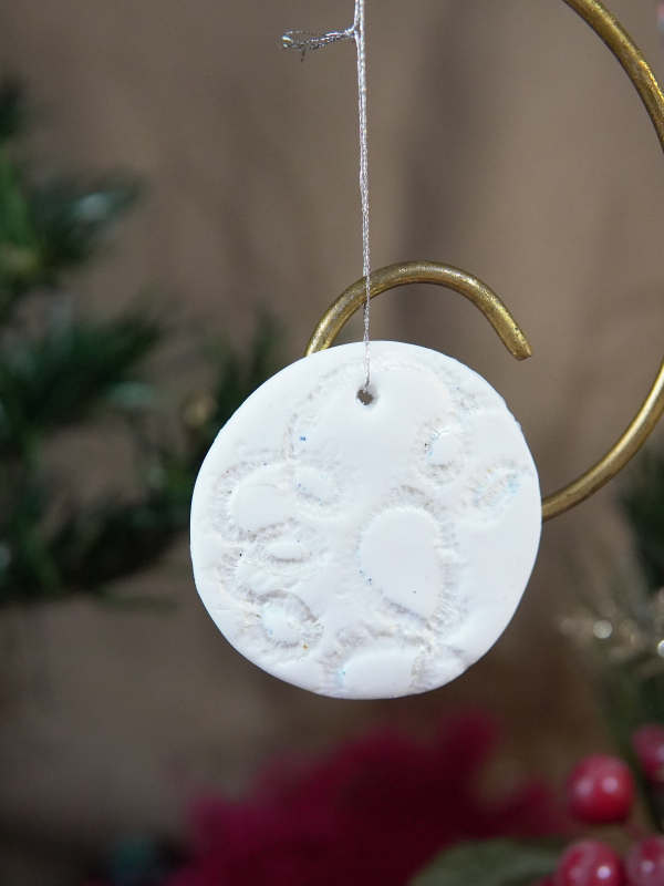 White round ornament showcasing a circular lace motif embossed into the surface