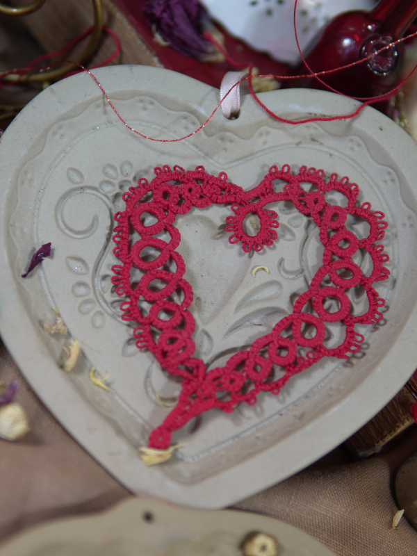 Red tatted lace heart ornament displayed on a ceramic heart tray.