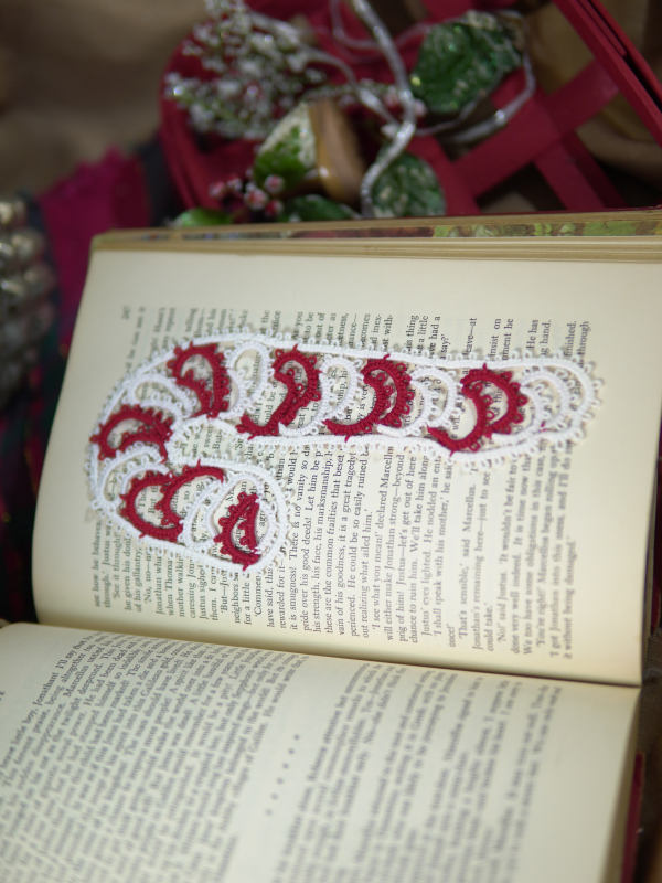 Red and white tatted candy cane bookmark lying on an open book with soft holiday