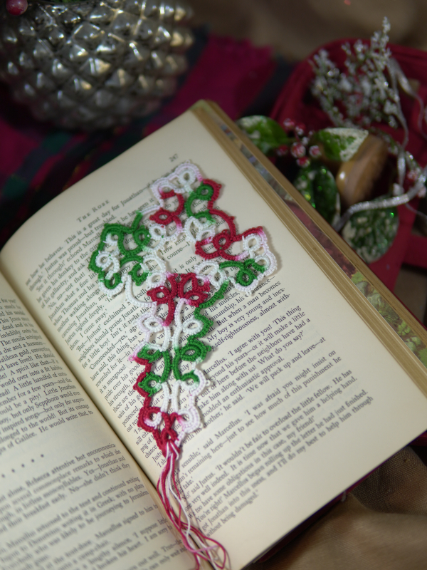 Handmade lace cross bookmark in Christmas colors photographed on the pages of a