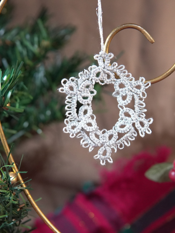 Handcrafted oval tatted lace ornament in classic silver Oval silver tatted lace ornament hanging on a holiday display
