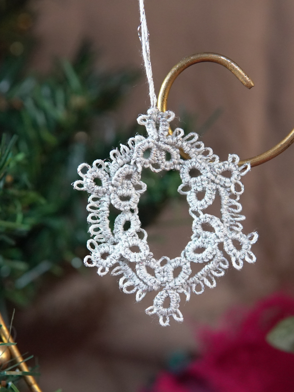 Delicate oval lace ornament to add timeless charm to your holiday décor. Tatted oval lace ornament hanging in front of Christmas backdrop