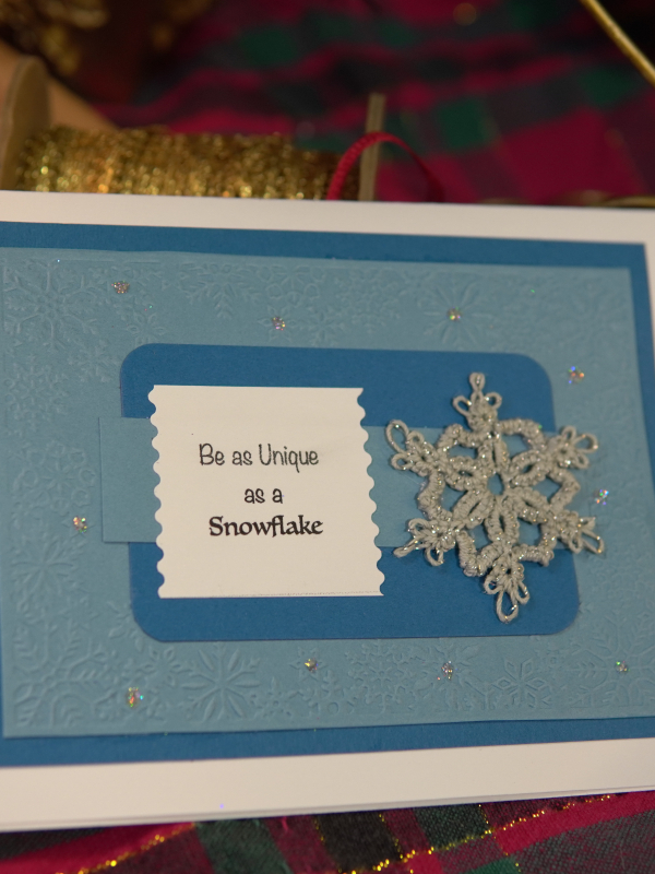 Detail shot of a tatted lace snowflake attached to layered cardstock in icy blue