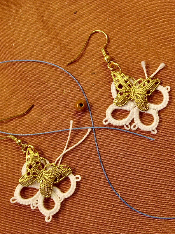 Brass butterfly earrings framed with white tatted lace.