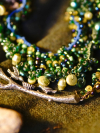 Close-up of green and brown lace necklace on forest backdrop