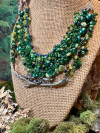 Layered green, brown, and blue tatted woodland necklace on display