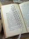 White tatted lace bookmark with tassel resting on the pages of an open book