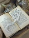 White tatted lace bookmark with tassel resting across pages of an open book