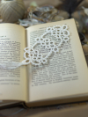 Handmade white lace bookmark displayed on open vintage book pages