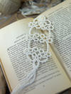 White tatted bookmark with tassel lying on an open book with soft decor