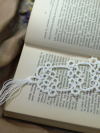Ivory white tatted bookmark lying across open antique book