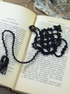 Black tatted lace teapot bookmark resting on the pages of an open book