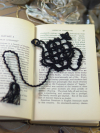 Handmade black lace teapot bookmark displayed across open vintage book
