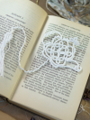 Handmade white lace teapot bookmark displayed across open vintage book