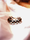 Black tatted bracelet with bronze crystal beads laid flat on white silk fabric