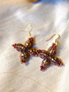 Starweft Blossom earrings resting on white silk fabric