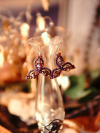 Rose and crystal tatted earrings displayed on a tall glass vase.