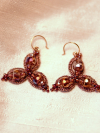 Three-petal tatted earrings with crystals on soft fabric.