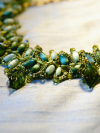 Necklace laid on white fabric showing green glass leaf drops