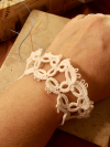 Overhead view of white tatted lace bracelet with picot edging.