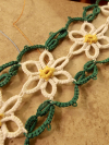 Close-up of white lace daisies linked with green tatted loops