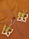 Brass butterfly earrings framed with white tatted lace.