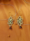 Wanderbloom Trefoil earrings glowing in warm sunlight on an earthy background