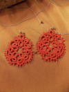 Red lace medallion earrings on fabric background