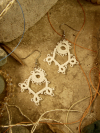 Close-up of lace earrings on a stone tile.