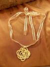 Yellow tatted rose necklace on sheer ribbon, displayed on warm fabric.
